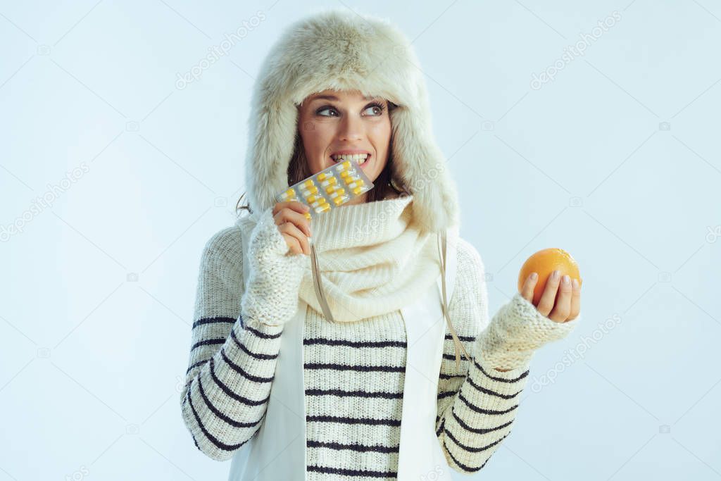 concerned woman with orange biting blister pack of vitamins