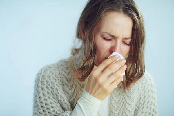 Donna con tovagliolo tosse su sfondo blu chiaro inverno — Foto Stock