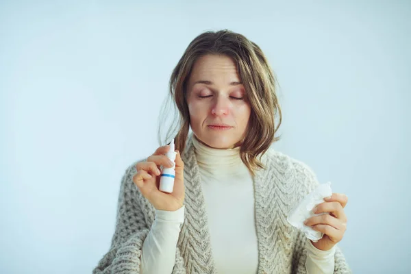 Enferma moderna mujer de 40 años con servilleta usando aerosol nasal — Foto de Stock