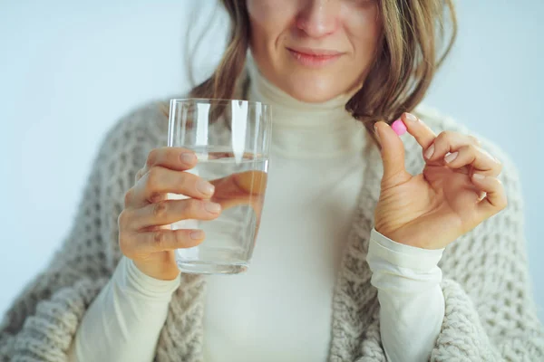 Крупный план на больной современной домохозяйке с чашкой воды показывая таблетки — стоковое фото