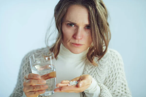 Zaniepokojona kobieta z filiżanką wody gospodarstwa wiele tabletek — Zdjęcie stockowe