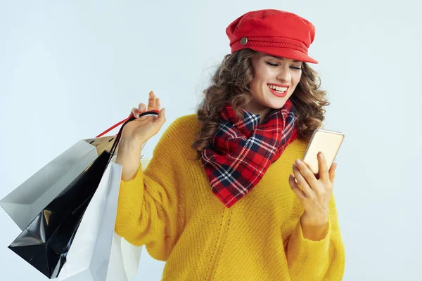 Smiling trendy middle age woman with shopping bags writing sms — Stock Photo, Image