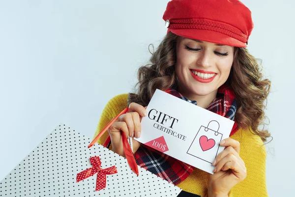 Alışveriş poşetleriyle gülümseyen kadın hediye çekine bakıyor. — Stok fotoğraf