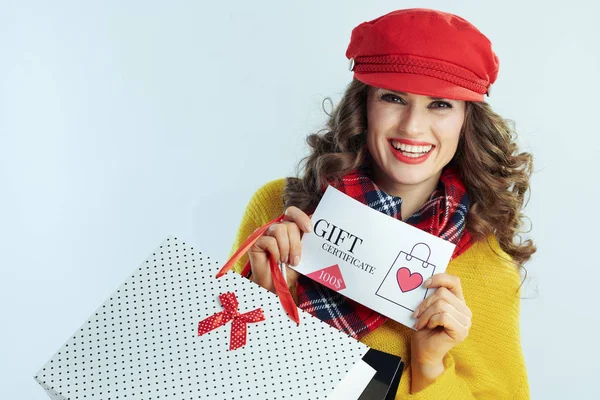 Sorridente donna moderna shopper mostrando buono regalo — Foto Stock