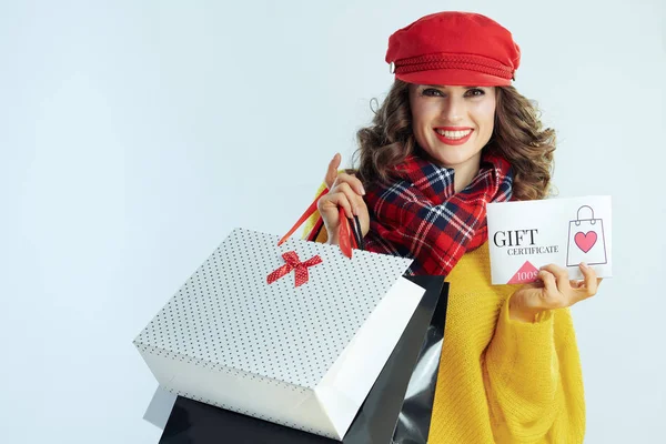Gelukkig vrouwtje met boodschappentassen met cadeaubon — Stockfoto