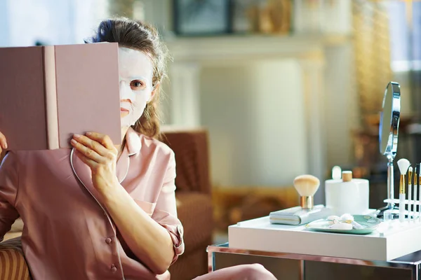 Beyaz Çarşaf Maskeli Zarif Orta Yaşlı Kadın Kitaptan Dışarı Bakıyor — Stok fotoğraf