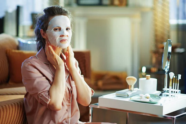 Modern Middle Age Woman Pajamas Applying White Sheet Facial Mask — Stock Photo, Image