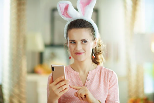 Σκεπτική 40Χρονη Γυναίκα Ροζ Μπλούζα Και Πασχαλινά Αυτιά Λαγού Smartphone — Φωτογραφία Αρχείου