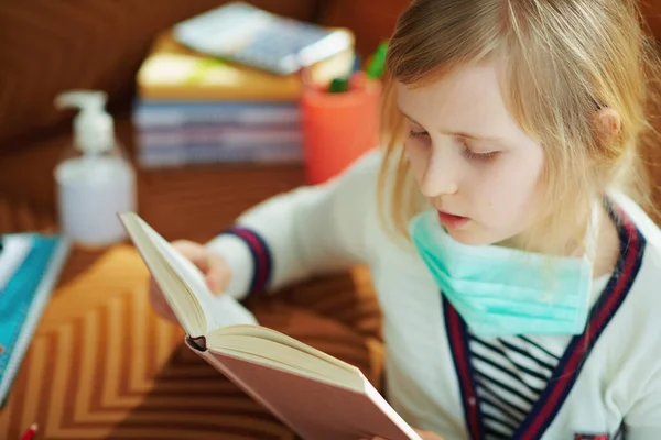 Young Girl White Striped Shirt Medical Mask Sitting Sofa Reading — Stock Photo, Image