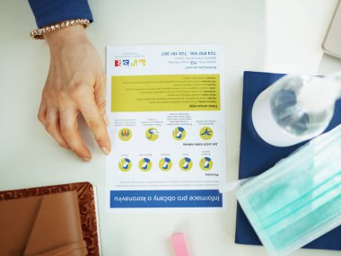 PRAGUE - 24 Mart 2020: Masadaki 40 yaşındaki iş kadınının Coronavirus hakkında bir broşür okuması.