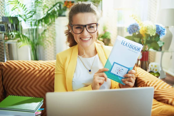 Joven Sonriente Jeans Chaqueta Amarilla Con Portátil Mostrando Libro Texto — Foto de Stock