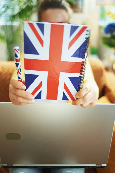 晴れた日に自宅で頭の前で英国のフラグノートブックを保持ノートパソコンを持つ学習者の女性の閉鎖 — ストック写真