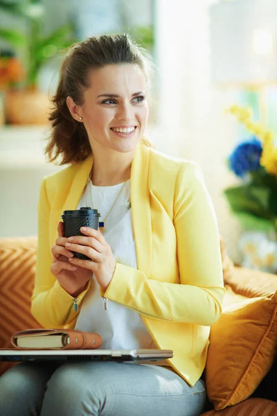 청바지와 노란색 자켓을 소파에 여학생은 거실에서 온라인으로 준비가 노트북 커피를 — 스톡 사진