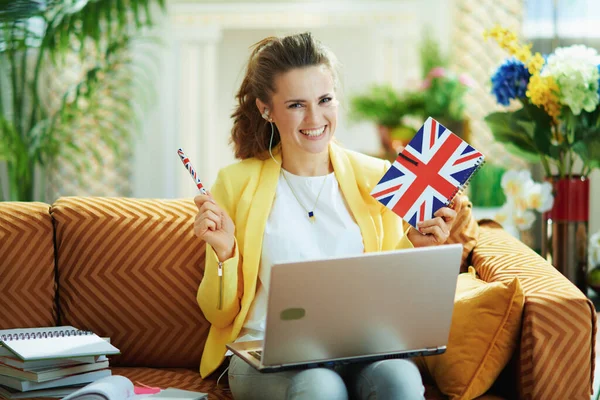 Улыбающаяся Летняя Женщина Джинсах Желтой Куртке Ноутбуком Показывающим Флажок Великобритании — стоковое фото