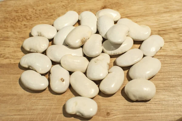A pile of big white dry navy beans closeup on wooden board