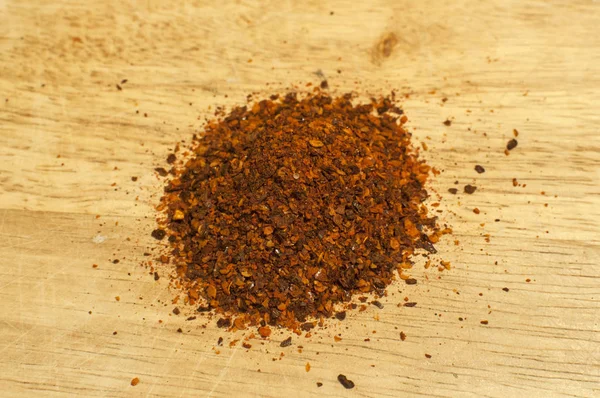 一堆干磨碎的粗地面红辣椒片和种子香料粉特写木板 — 图库照片