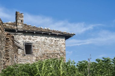Kırsal kesimdeki taştan bir ev, güneşli bir yaz gününde.
