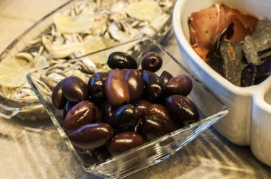 Bowls with olives and other appetizers on table closeup