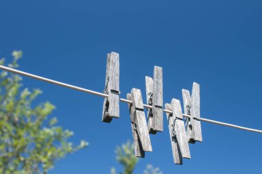 Yıkanmış ahşap kıskaçlar mavi gökyüzü arka planında asılı.