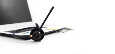 VoIP kulaklık, dizüstü bilgisayarın klavyesine not kağıdı ve kalem. Çağrı merkezi ve müşteri hizmetleri yardım masası için iletişim desteği. Beyaz arka planda izole edilmiş. Üst görünüm düz arkaplan. Metin tasarımı için boşluk