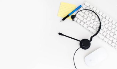 VoIP kulaklık, dizüstü bilgisayar klavyesine kalem ve kağıt. Çağrı merkezi ve müşteri hizmetleri yardım masası için iletişim desteği. Beyaz arka planda izole edilmiş. Üst görünüm düz arkaplan. Metin tasarımı için boşluk