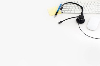 VoIP kulaklık, dizüstü bilgisayar klavyesine kalem ve kağıt. Çağrı merkezi ve müşteri hizmetleri yardım masası için iletişim desteği. Beyaz arka planda izole edilmiş. Üst görünüm düz arkaplan. Metin tasarımı için boşluk
