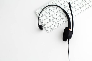 Laptop bilgisayar klavyesinde VOIP kulaklığı. Çağrı merkezi ve müşteri hizmetleri yardım masası için iletişim desteği. Beyaz arka planda izole edilmiş. Üst görünüm düz arkaplan. Metin tasarımı için boşluk
