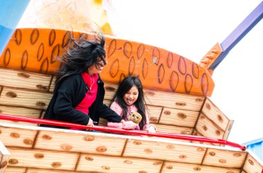 Anne ve kızı lunapark oyununda gülümsüyor.