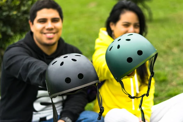 Two smiling friends showing helmet