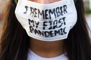Kız, yüzünde koruyucu steril tıbbi maske takan genç bir kadın Asya sokak gösterilerinde, avuçlarında, ellerinde kameralara bakıyor. Hava kirliliği, virüs, Çin salgını koronavirüs konsepti.