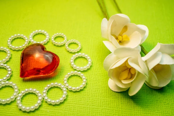 Il cuore di vetro rosso è circondato da anelli di perline e fiori di carta, carte fatte a mano — Foto Stock