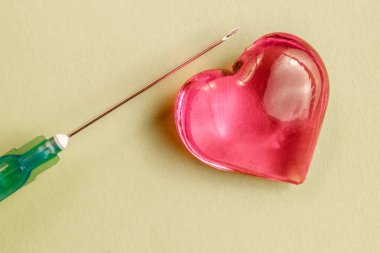 Cam kalp bir tıbbi şırınga oyun uzanan renkli kağıt üzerinde