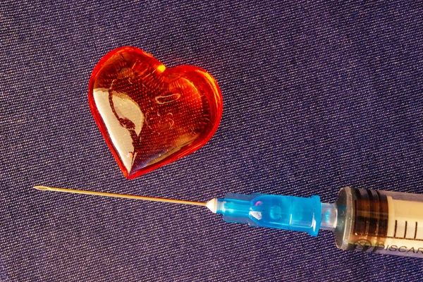 Siringa medica vicino al cuore di vetro — Foto Stock