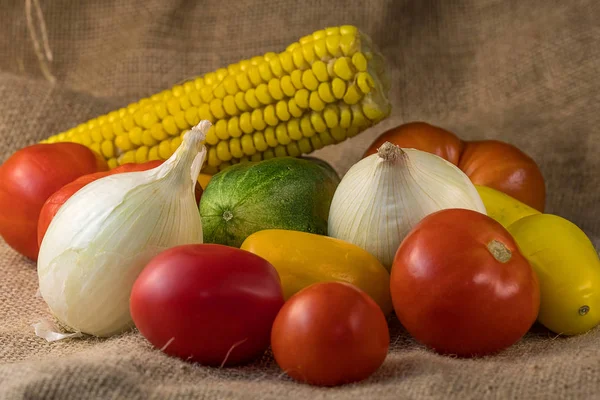 Sayuran yang berbeda terletak bersama-sama di satu meja, tomat, bawang bombay dan jagung — Stok Foto
