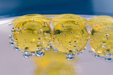 Su altında. Balık yağı omega 3 kapsülleri mavi zemin üzerine.