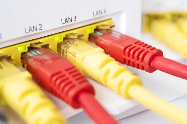 Κόκκινο και κίτρινο σκοινιά μπαλωμάτων είναι εισάγεται στο router λευκού χρώματος. σπίτι στο διαδίκτυο — Φωτογραφία Αρχείου