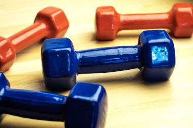 Evde Fitness için kırmızı ve mavi dambıl, çelik ahşap yüzey üzerinde dağınık, ahşap arka plan