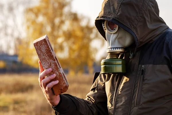 El hombre de la máscara de gas mira el ladrillo, un estudio de los objetos infectados peligrosos examen cuidadoso — Foto de Stock