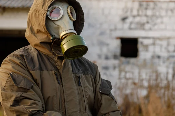 Old brick wall in the background on the front man in green suit and gas mask, ready for war — Stock Photo, Image