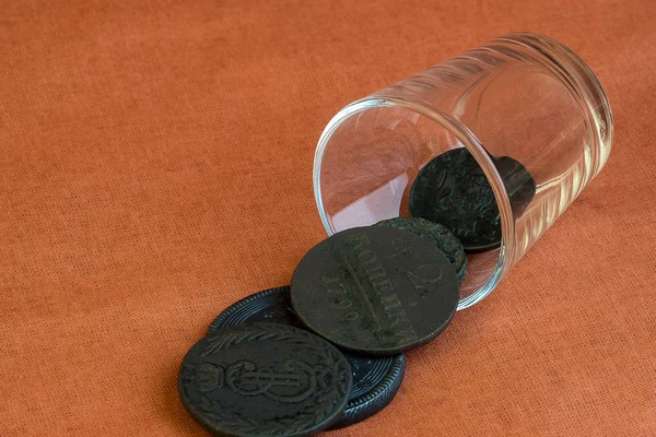 Monedas de un vidrio cayeron sobre un paño de color naranja — Foto de Stock
