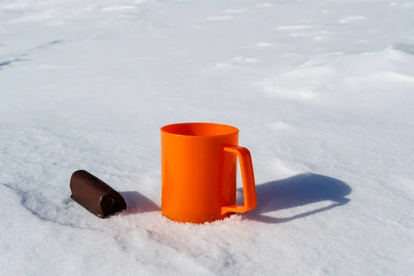 Taza de plástico naranja y al lado de galletas de chocolate en la nieve, caliente y frío —  Fotos de Stock