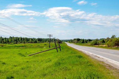 Şiddetli rüzgârlar sonucu düşen elektrik desteği yol boyunca duruyor.