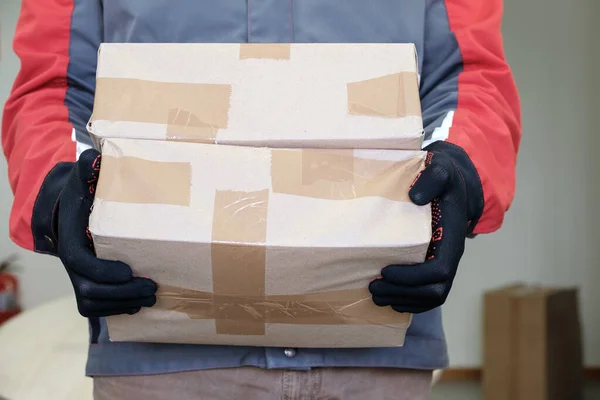 Homem trabalhador segurando duas embalagens seladas em papel marrom e envolto com fita adesiva — Fotografia de Stock