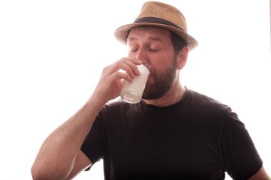 Şapkalı beyaz adam beyaz arka planda kefir içiyor.