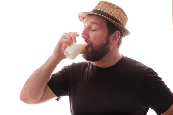 Un uomo beve latte prodotto chiudendo dal piacere degli occhi lo sfondo è bianco — Foto Stock