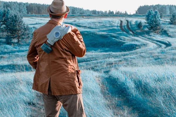 Un homme avec un costume brun et debout sur le masque à gaz épaule dans le fond de l'herbe bleue — Photo