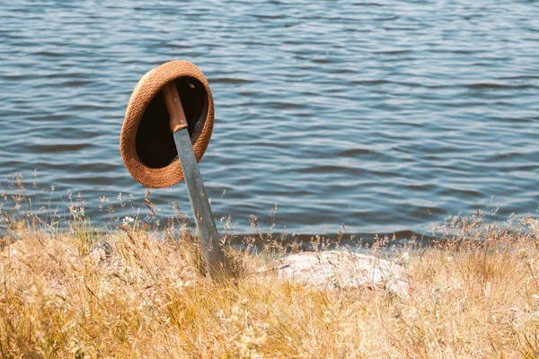 Na costa do lago preso na espada de terra sobre ele pendura um chapéu com um sol brilhante dia de verão borda — Fotografia de Stock