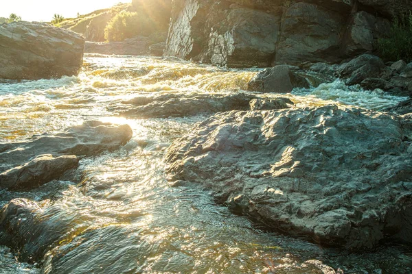 Taşların arasında bir dağ nehrinin hızlı nehirleri parlak güneşin ardından parlıyor. — Stok fotoğraf