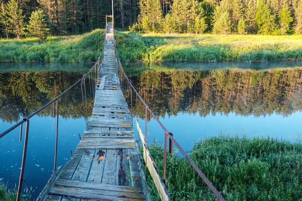 Hängebrücke über den Fluss im Fluss spiegelt das Ufer wider, an dem der Wald — Stockfoto
