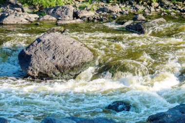 Aralarından akan hızlı bir dağ nehrinin fırtınalı suları